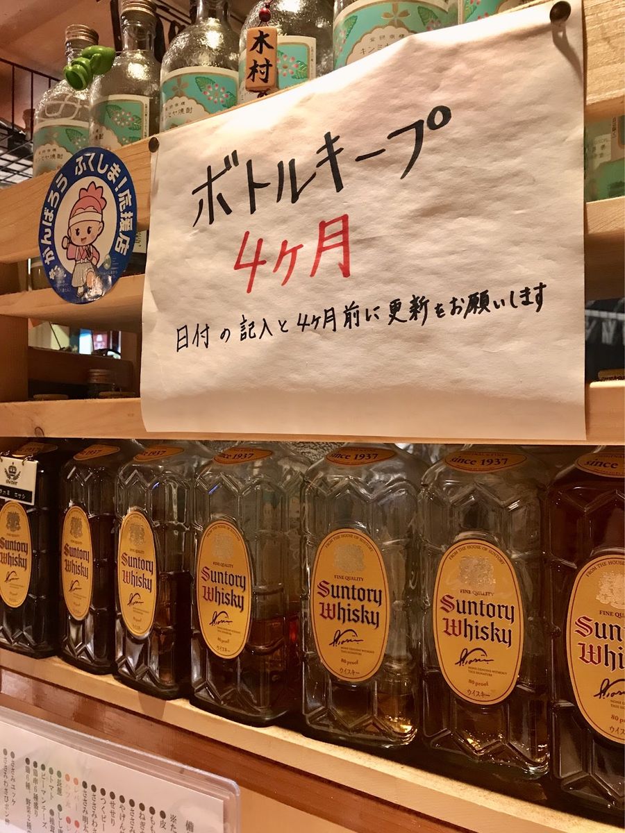 「ボトルキープ4ヶ月」の貼り紙と、棚に並ぶキープボトル